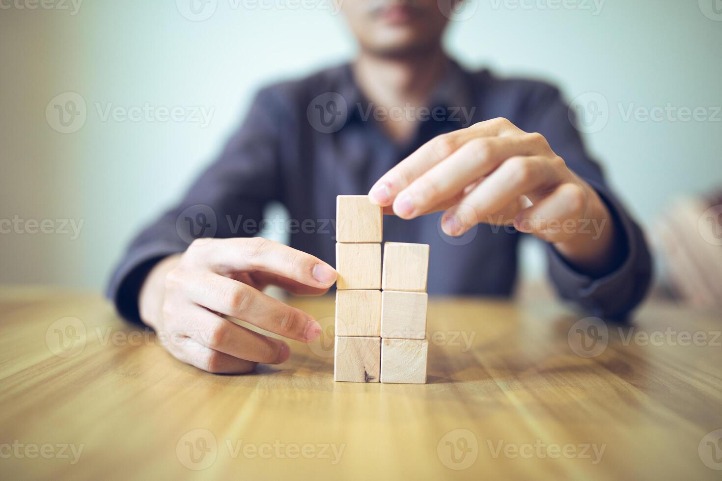 hand- strategisch plaatsen houten blokken in een traptrede ontwerp Aan een tafel, betekenend progressief succes en groei foto