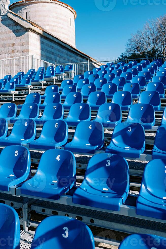 rijen van blauw stoelen in een stadion in de buurt een oude kerk foto