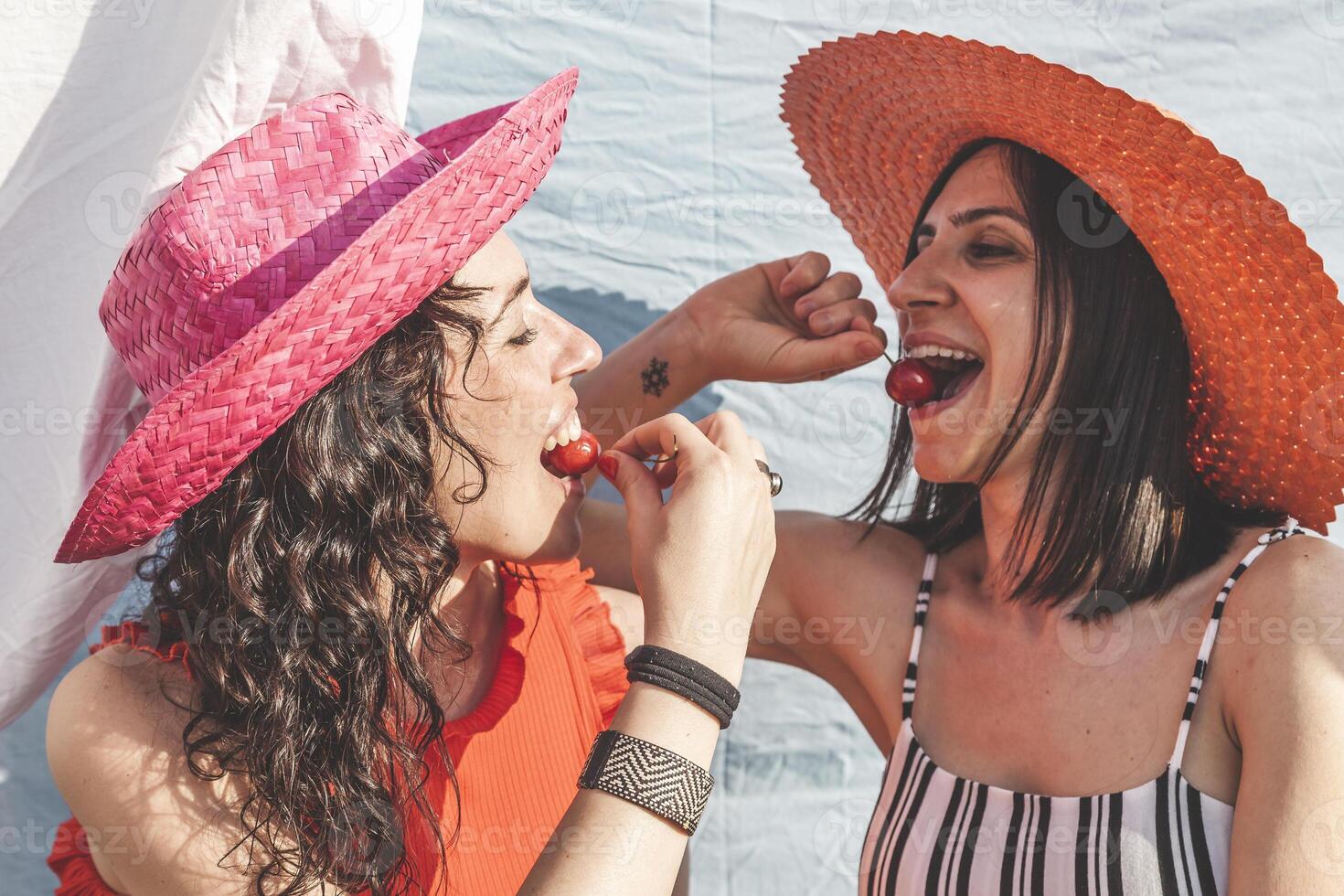 paar vrouw vrienden hebben pret terwijl aan het eten kersen Aan de daken foto