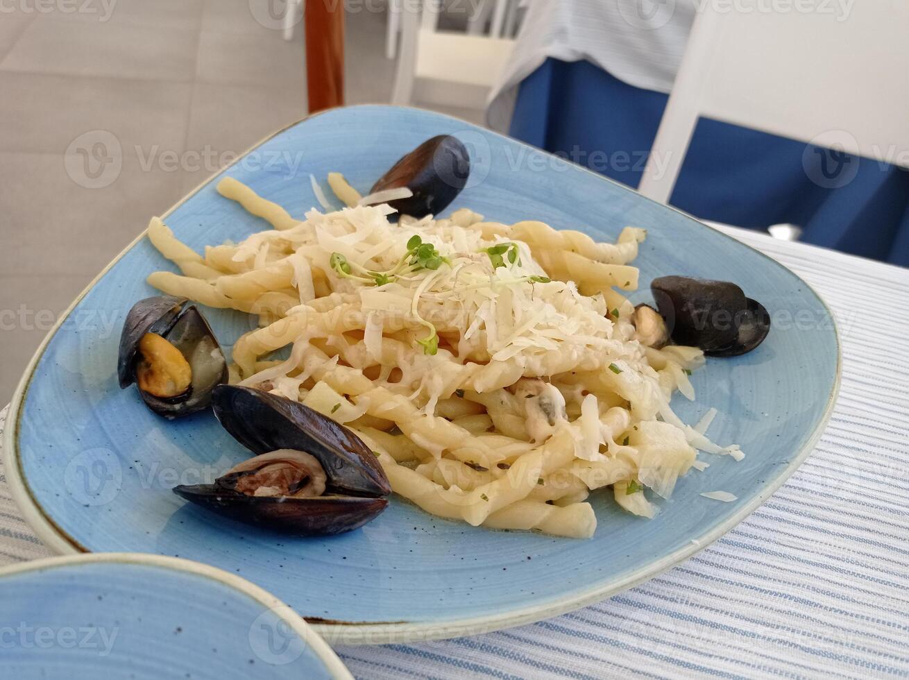 een mossel pasta schotel geserveerd met geraspt kaas en waterkers, procida, golf van Napels, Italië foto