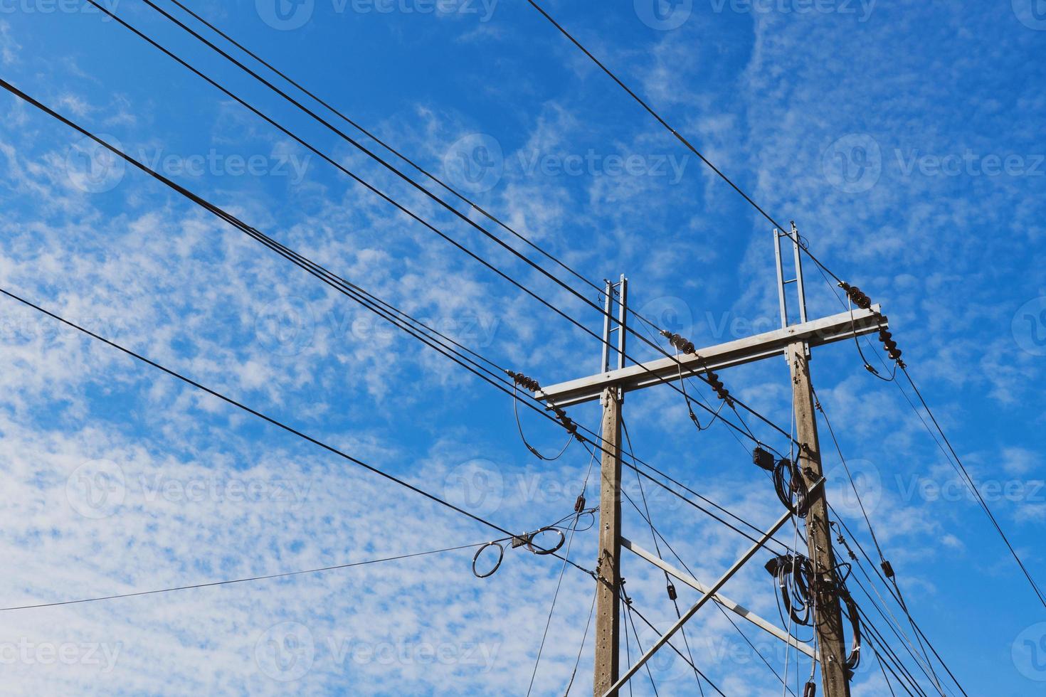 onderaanzicht van elektriciteitspaal onder bewolkte blauwe lucht foto