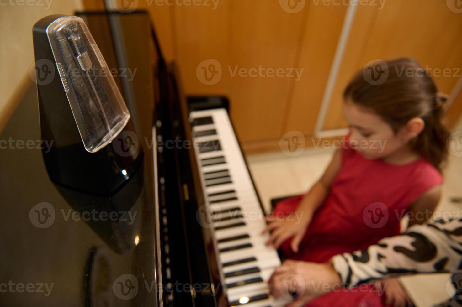 weinig kind meisje hebben een piano les met haar leraar Bij huis. weinig kind meisje zetten haar vingers Aan ebbehout en ivoor sleutels, creëren ritme van geluid, componeren melodie en het zingen Kerstmis lied foto