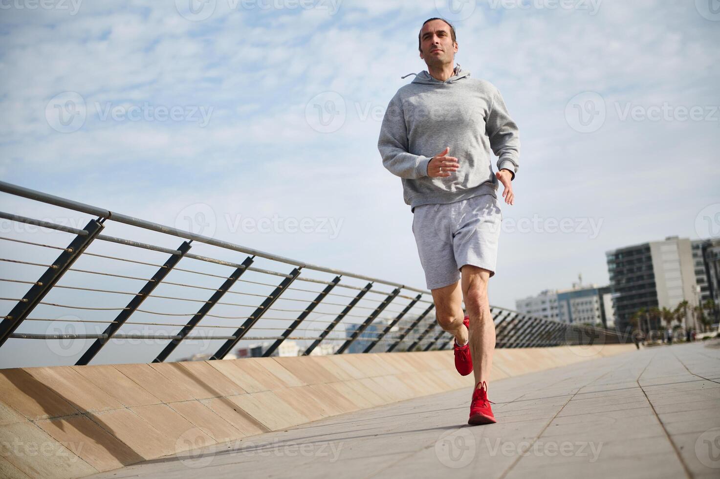 knap sportman, atletisch Mens rennen Aan de brug Aan zonnig dag, genieten van zijn ochtend- joggen Aan de promenade foto