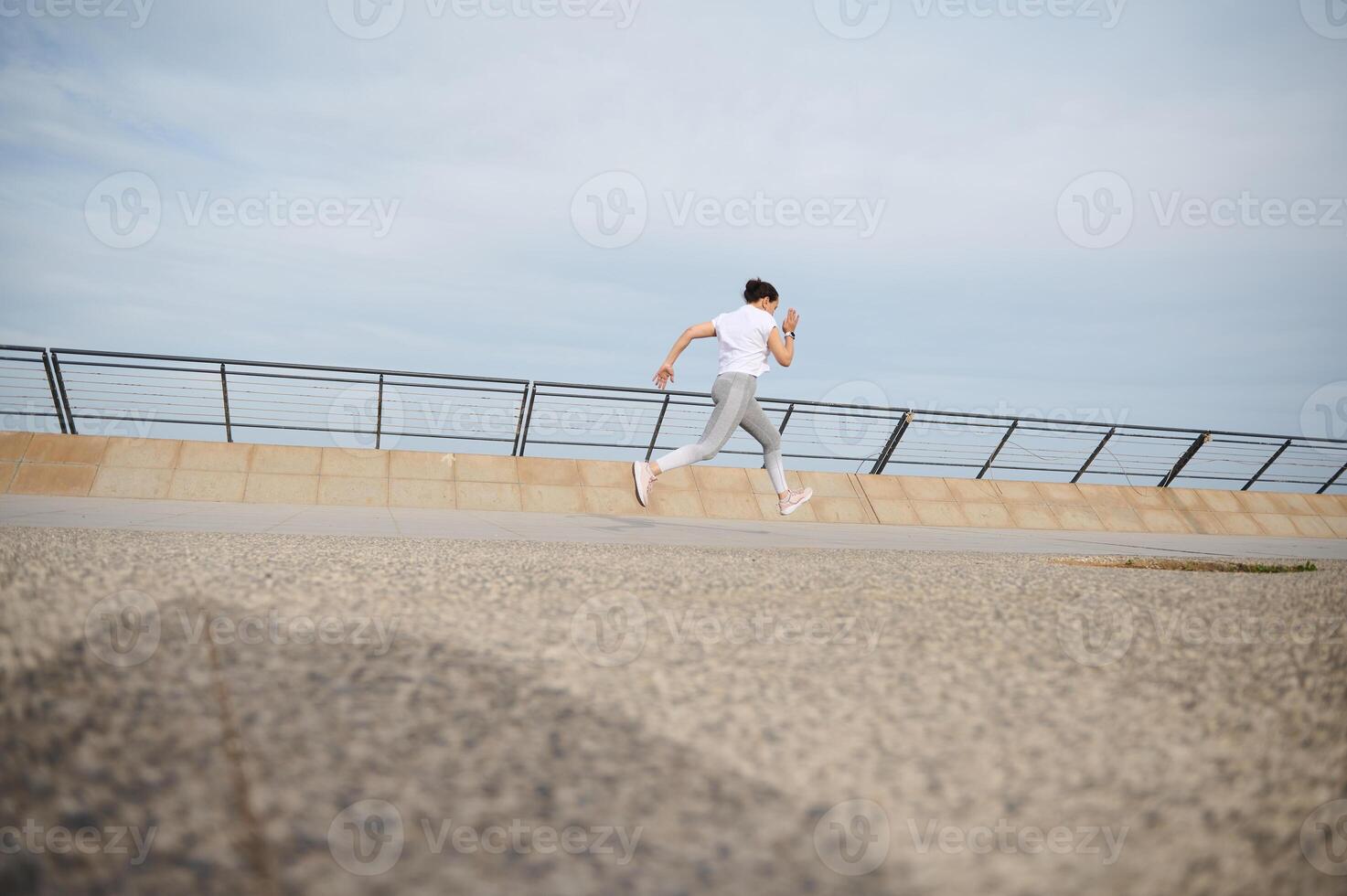 terug visie millennial vrouw loper in sportkleding rennen joggen Aan brug in stad, oefenen Aan de brug Aan een warm zonnig dag foto