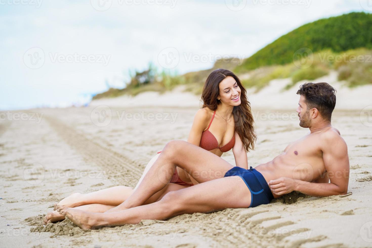 jong stel zit samen op het zand van het strand foto