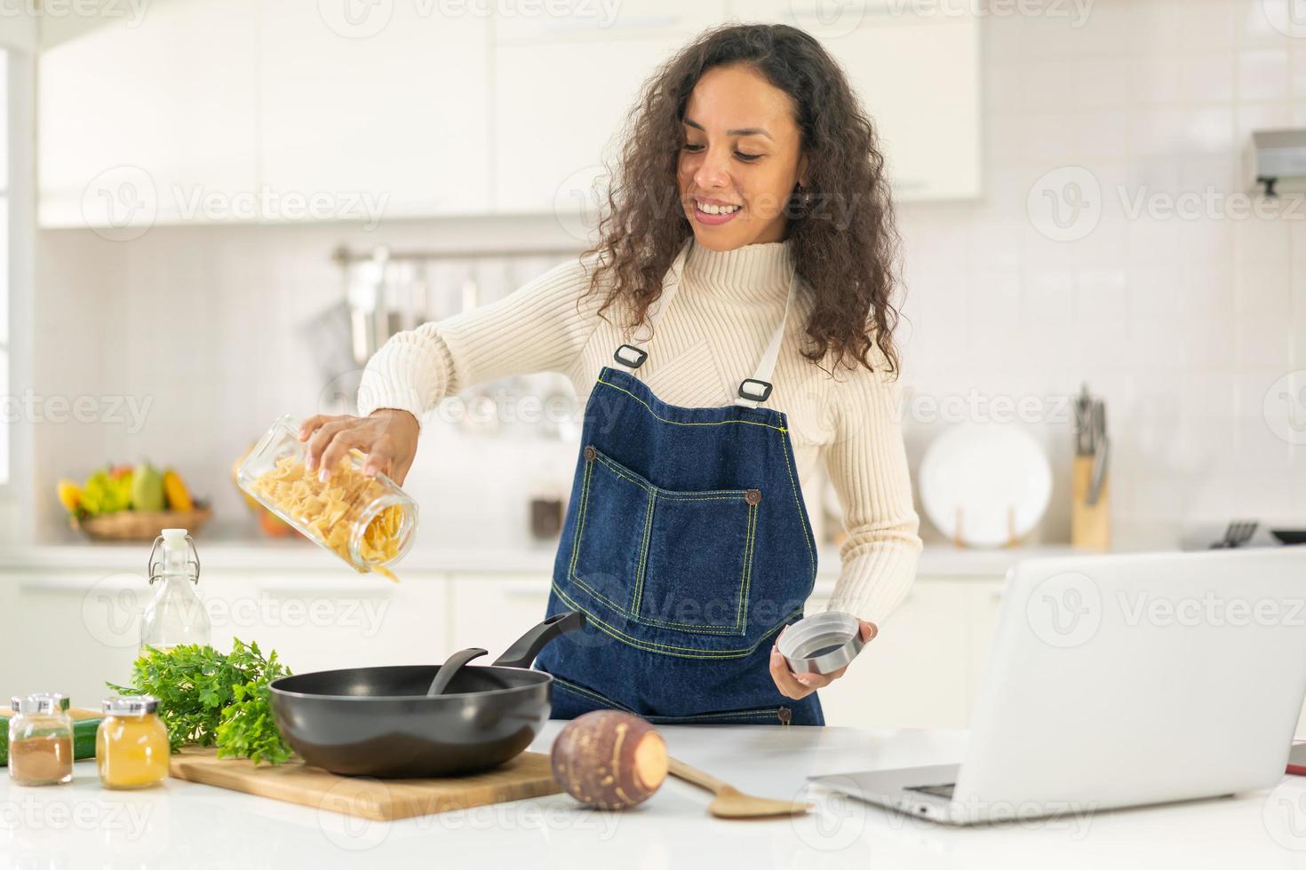 Latijnse vrouw die video opneemt en kookt in de keuken foto