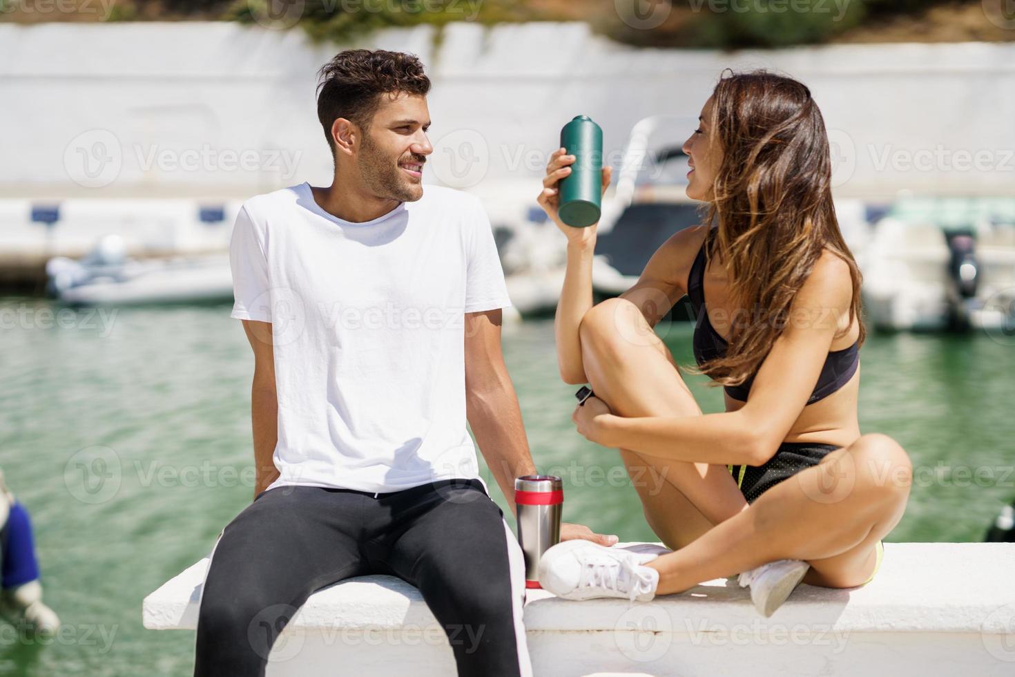 twee fitnessmensen hydrateren zichzelf met water in metalen blikjes terwijl ze een pauze nemen na het sporten. foto