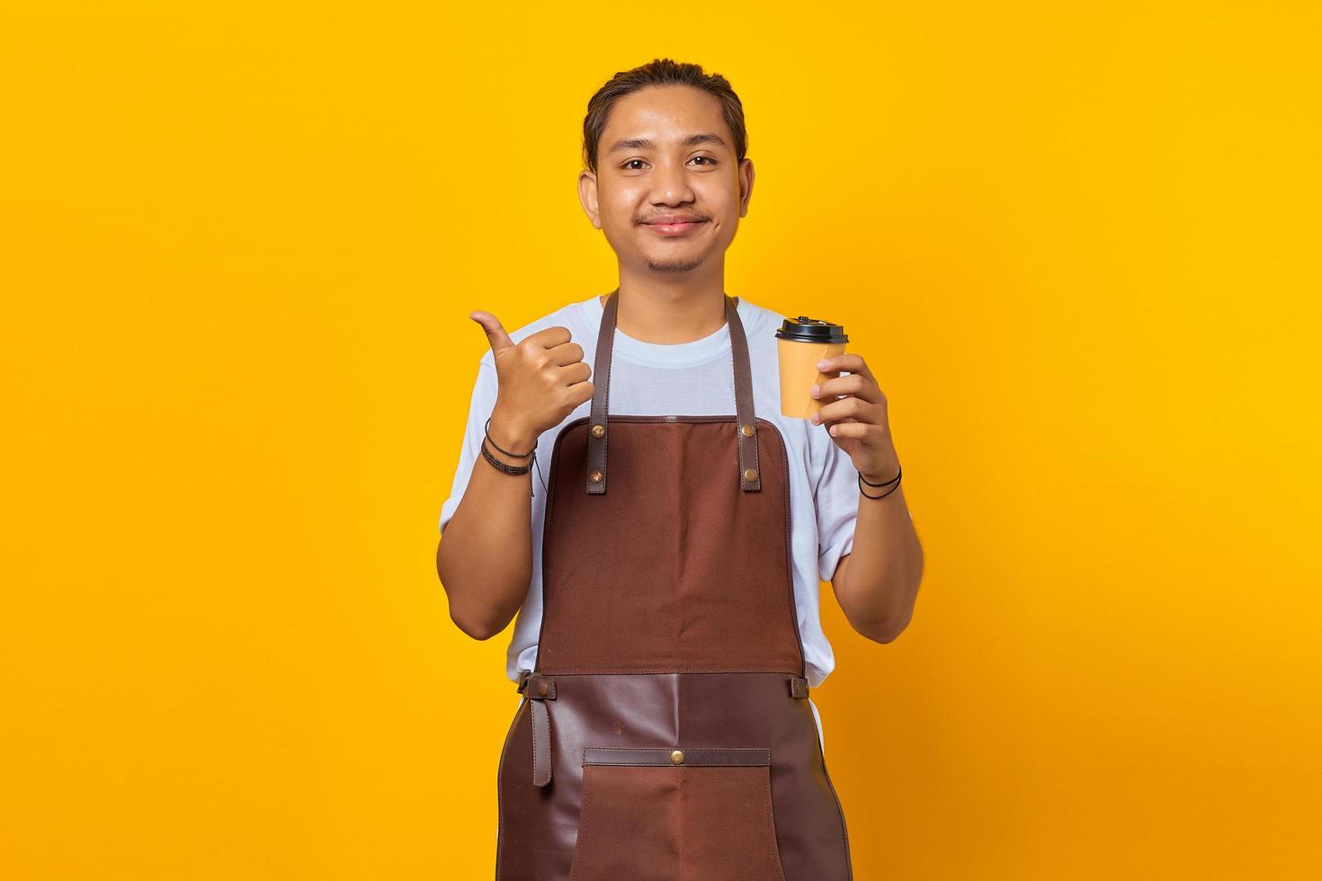 portret van een positieve vrolijke man die een papieren beker vasthoudt met een vinger die verkoopkorting op een gele achtergrond toont foto