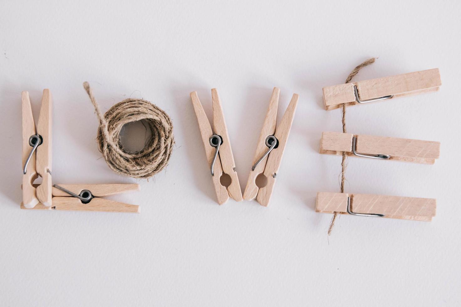 houten wasknijpers met touw op witte achtergrond met het opschrift het woord liefde. uitzicht van boven. plaats voor uw tekst foto