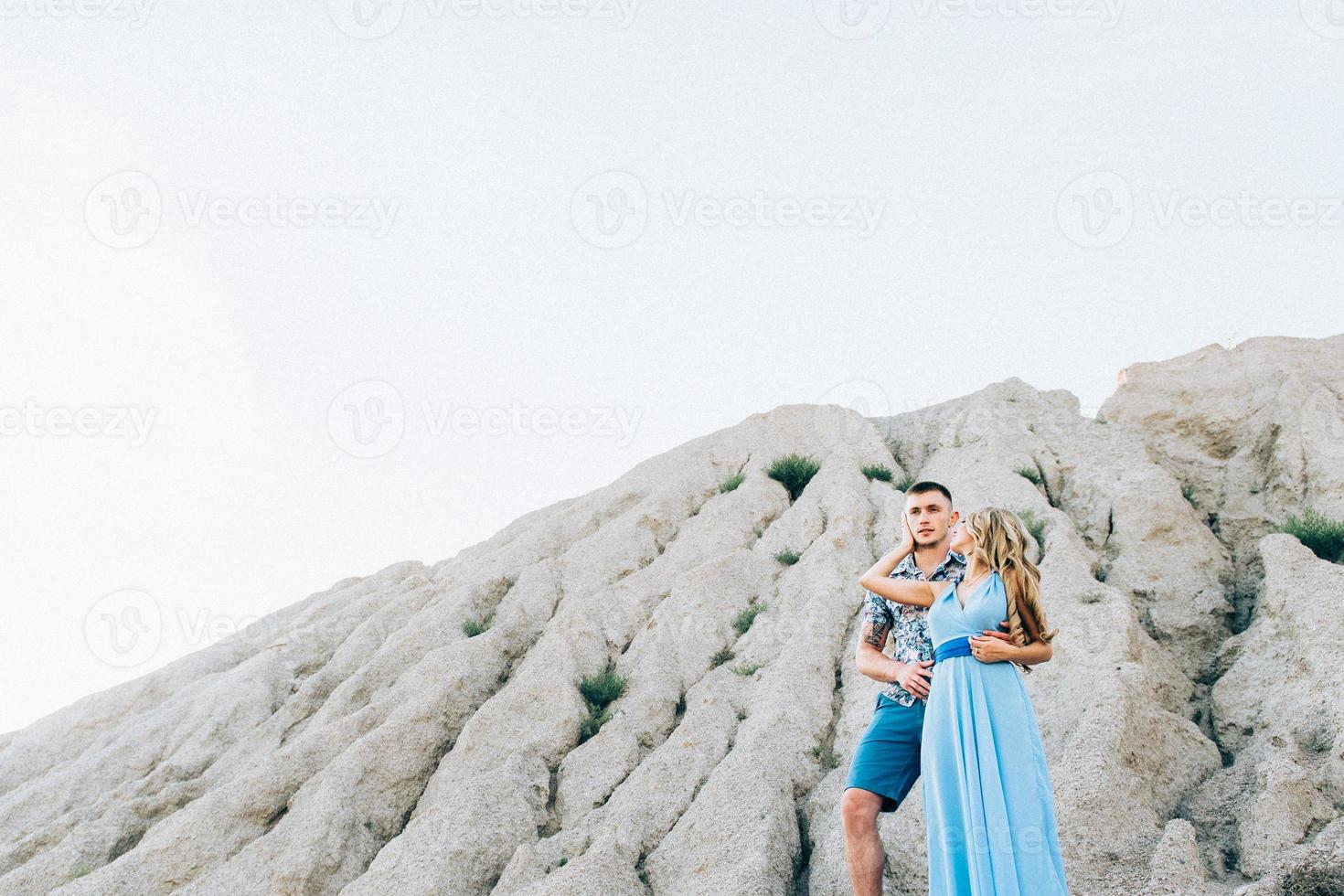 blond meisje in een lichtblauwe jurk en een man in een licht overhemd in een granietgroeve foto