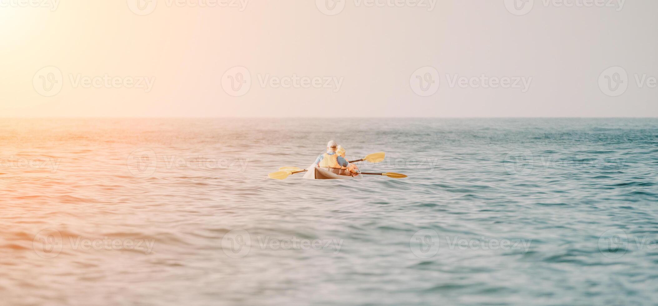 gelukkig paar kajaks in een opblaasbaar kajak Aan de zee Bij zonsondergang. paar kanoën in de zee in de buurt de eiland met bergen. mensen kajakken in leven jassen zeil. terug visie foto