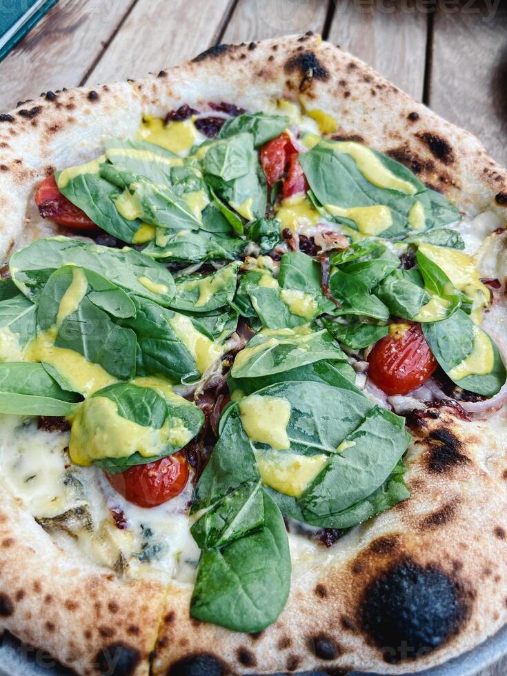 pizza met spinazie, kaas en tomaten staat Aan de tafel foto