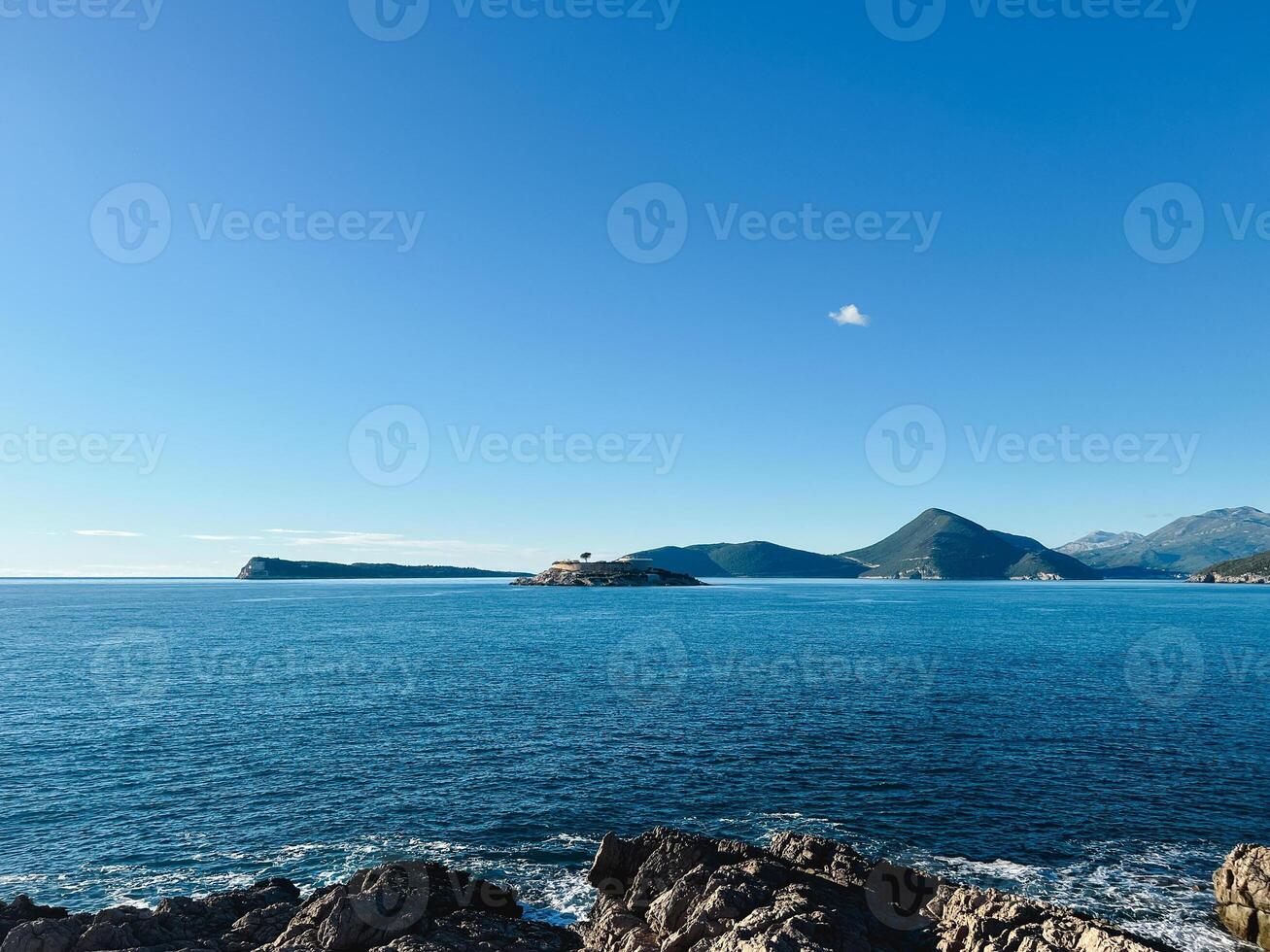 eiland in de zee tegen de backdrop van een hoog berg reeks en blauw lucht foto