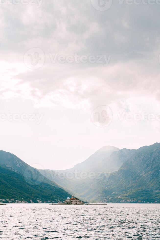 eiland van gospa od skrpjela in de zon met een berg reeks in de achtergrond. Montenegro foto