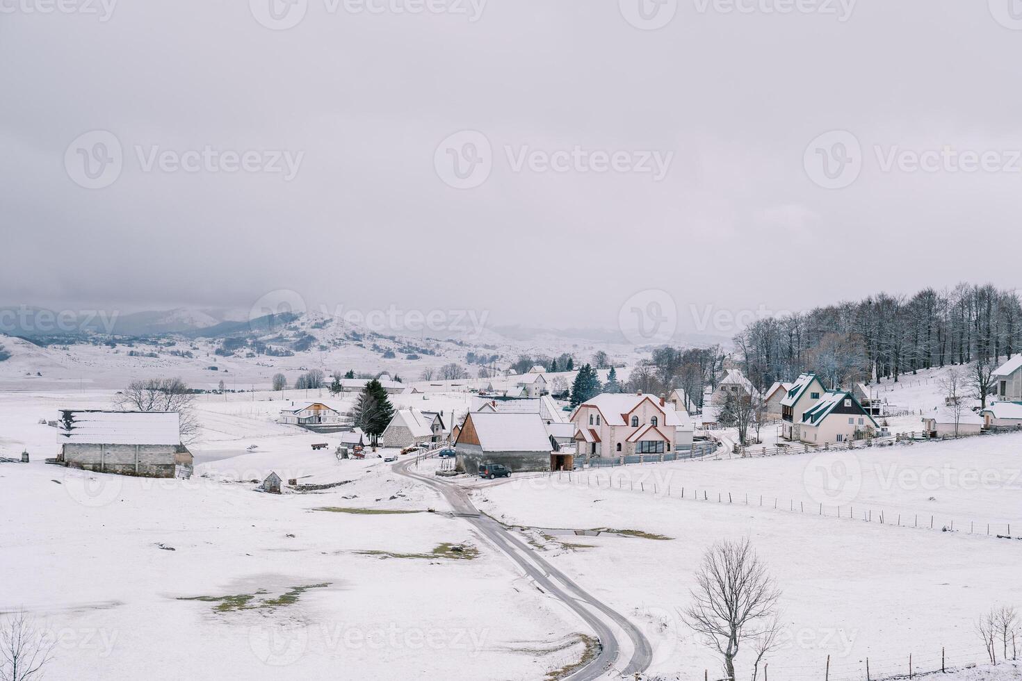 land weg in een klein met sneeuw bedekt dorp in een berg vallei foto