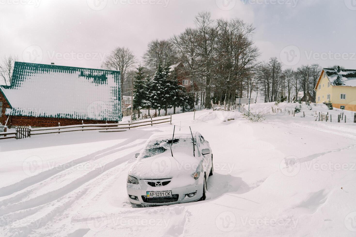 met sneeuw bedekt auto staat in een sneeuwjacht in een klein dorp foto