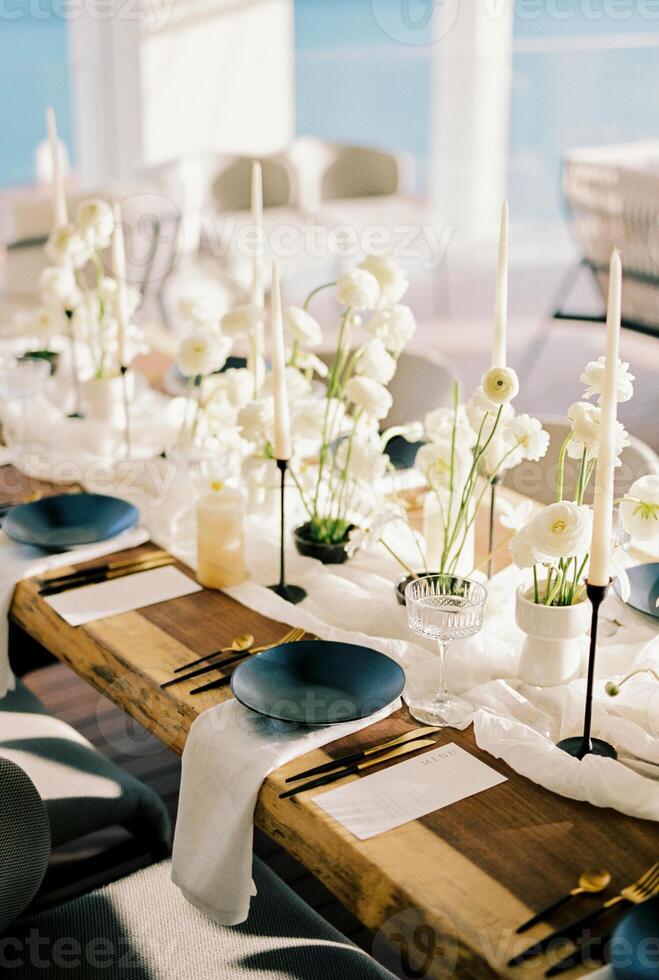 zwart borden Aan wit servetten staan Aan een feestelijk tafel met bloemen Aan een versmallen tafelkleed foto