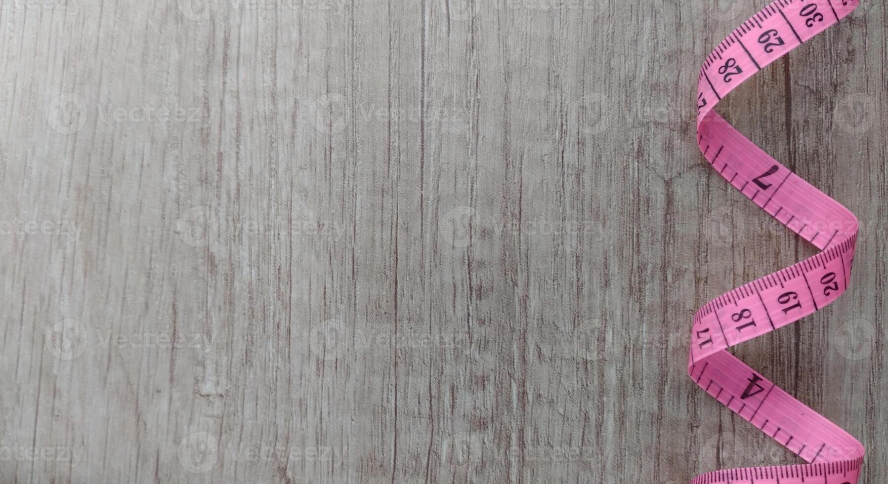 roze meten plakband Aan een hout achtergrond. gerold plakband met getallen foto