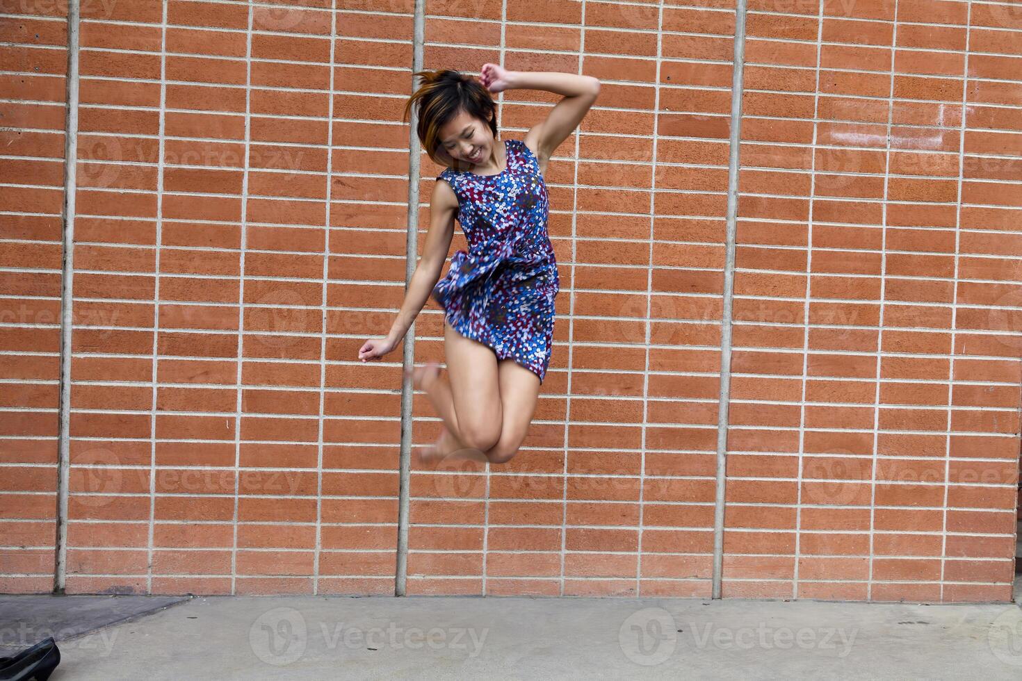 mager Aziatisch Amerikaans vrouw jumping in jurk foto