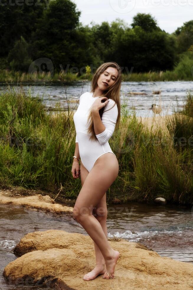 Kaukasisch tiener vrouw staand in wit maillots Bij rivier- foto