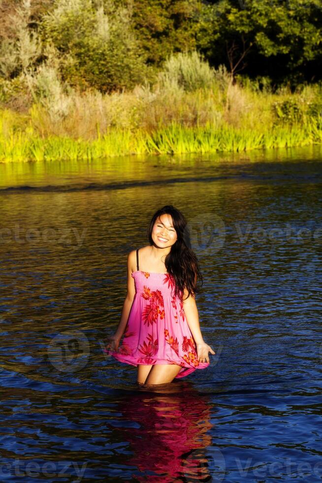 glimlachen Aziatisch Amerikaans vrouw staand in rivier- foto