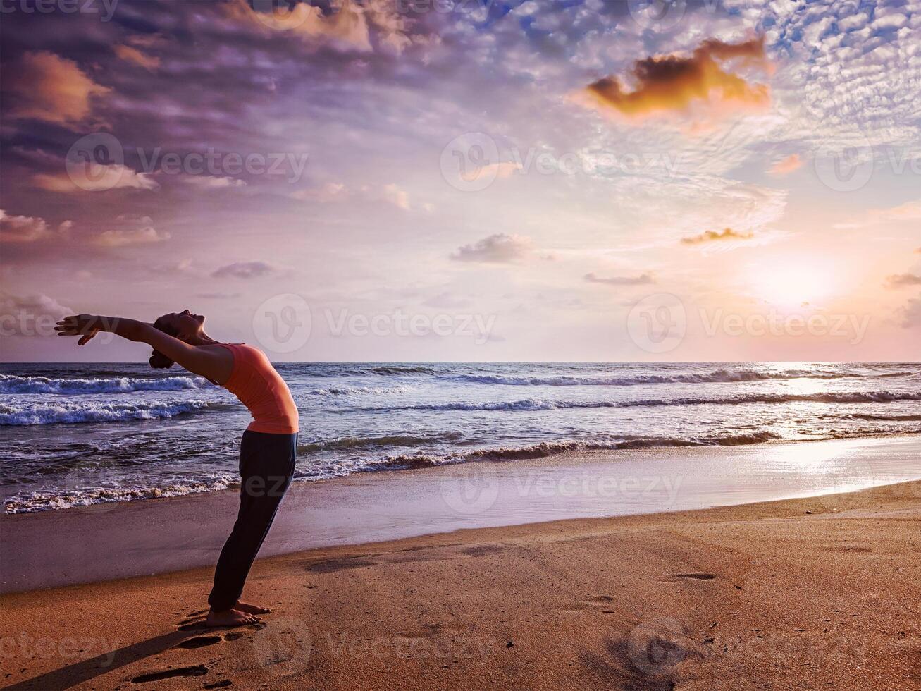 jong sportief fit vrouw aan het doen yoga zon begroeting surya namaskar foto