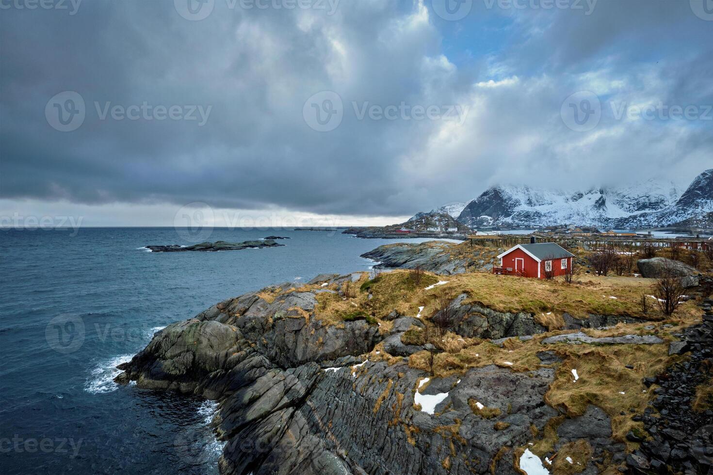 clif met traditioneel rood rorbu huis Aan lofoten eilanden, Noorwegen foto