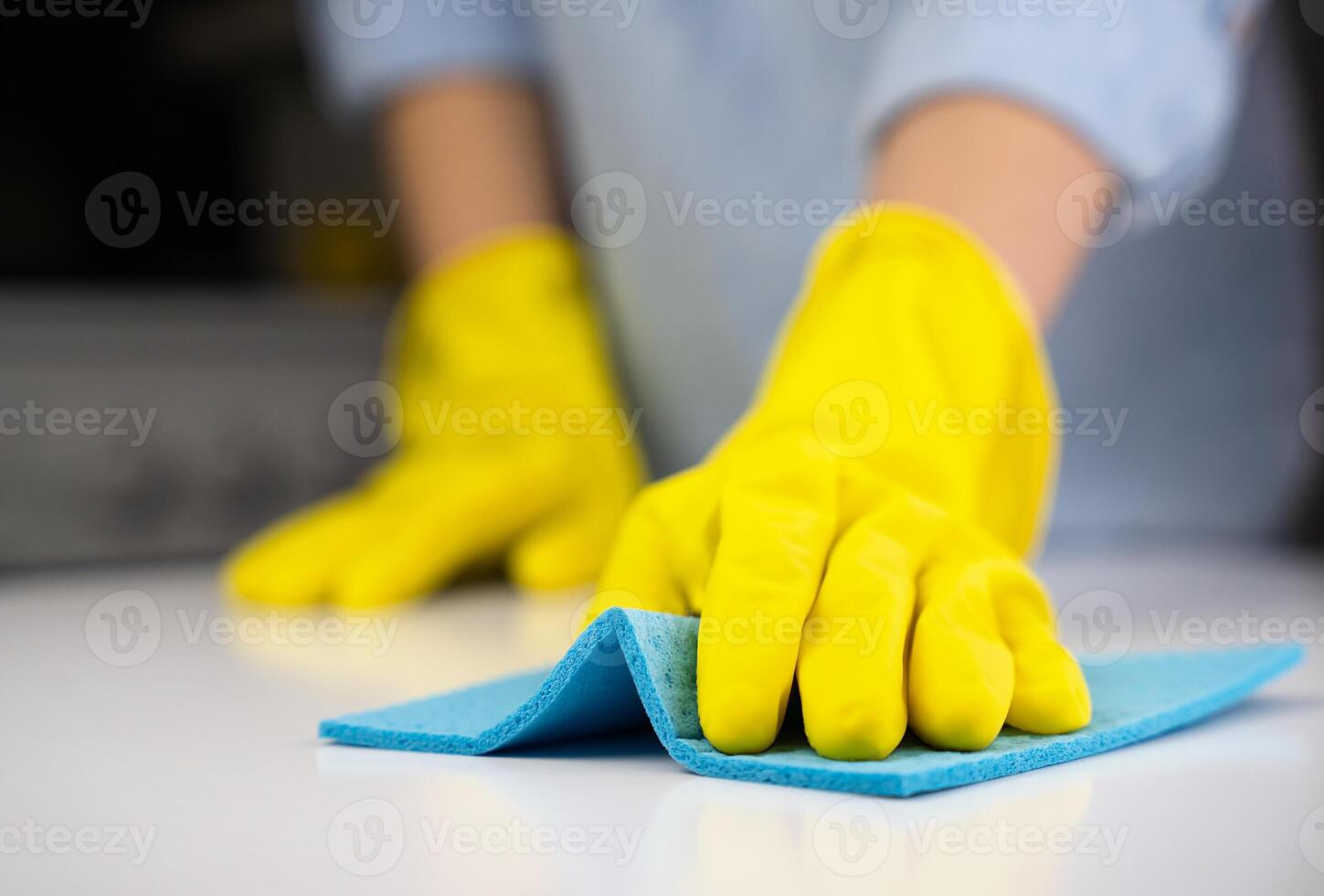 vrouw in geel rubber handschoenen doekjes de stof Aan de tafel met een vod. huishouding concept. detailopname. selectief focus. foto