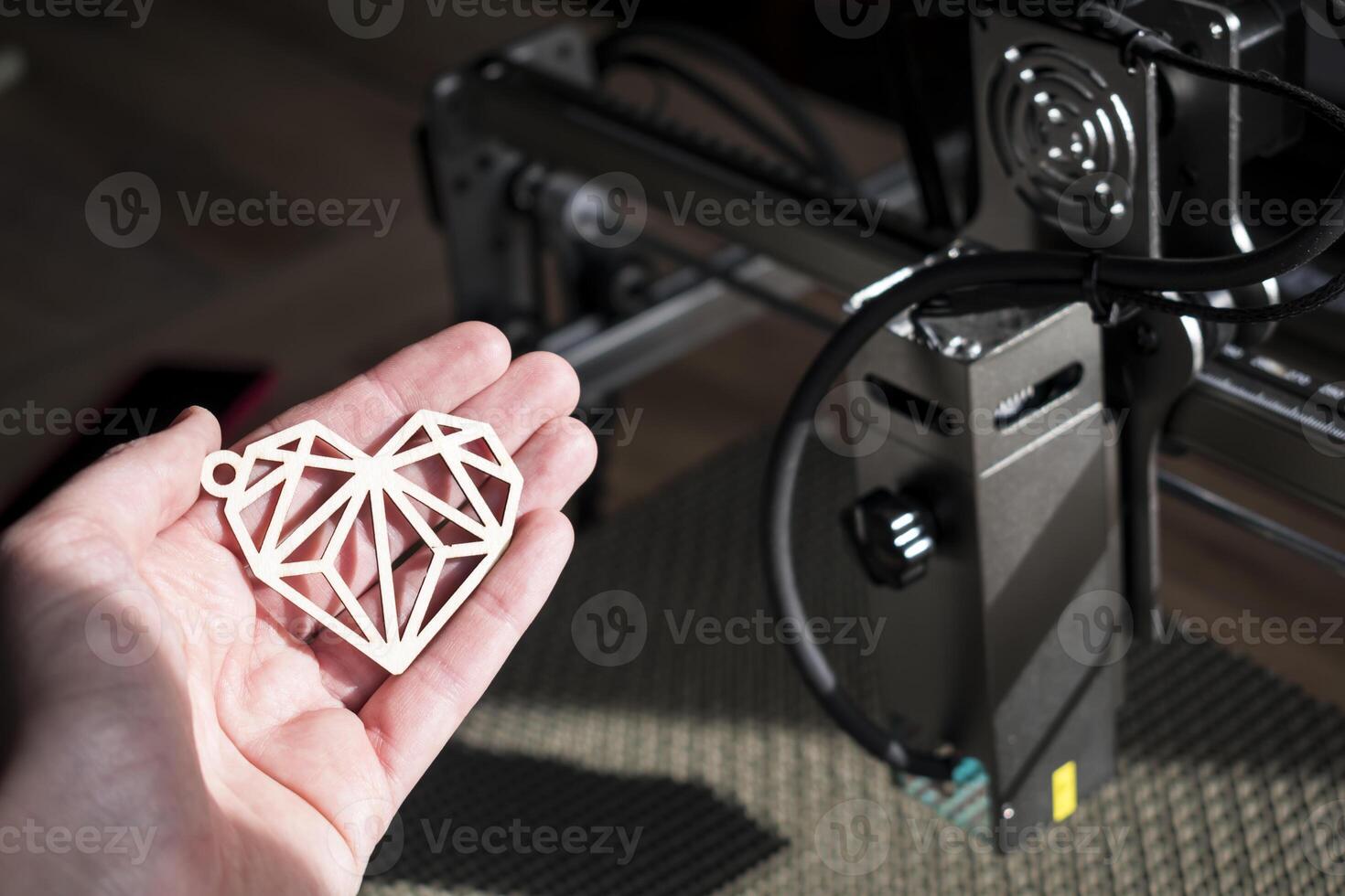 laser gravure en snijden, hand- Holding een voorbeeld van een besnoeiing uit houten hart foto