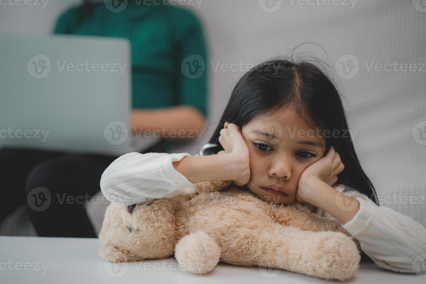 een jong meisje is zittend Aan een bankstel met een teddy beer in haar ronde foto