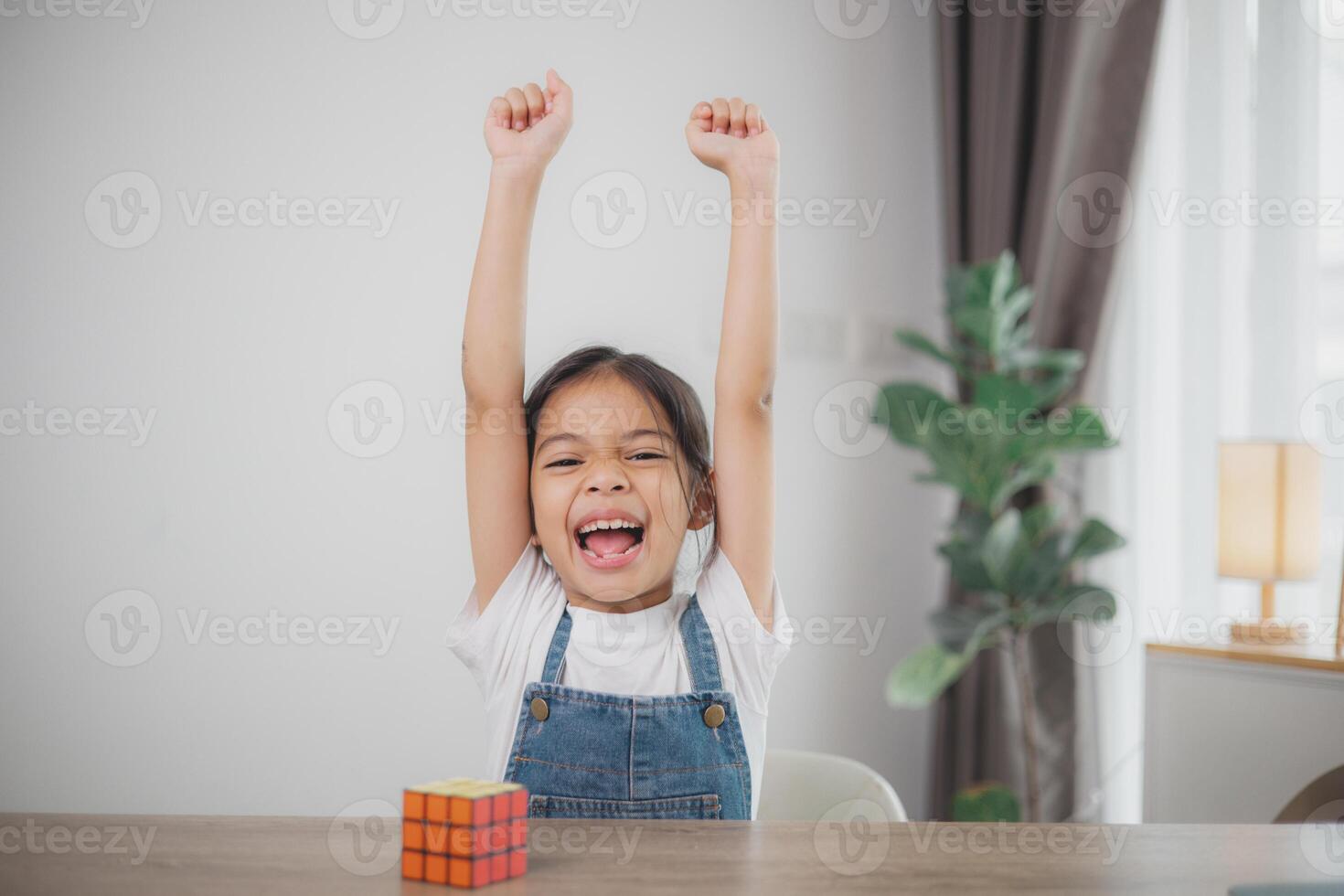een jong meisje is zittend Bij een tafel met een rubik's kubus in voorkant van haar foto