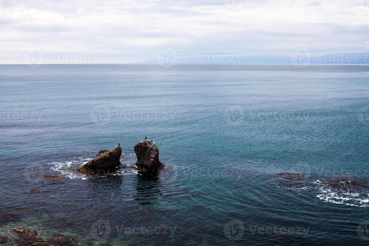 twee groot rots in zeeor oceaan water foto