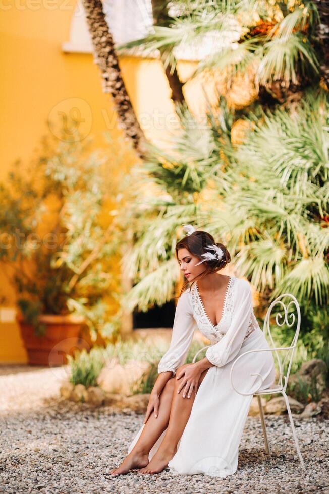 een mooi bruid is zittend Aan een stoel en glimlachen in haar ondergoed en dressing japon De volgende naar een villa in Italië.ochtend van de bruid in Toscane foto