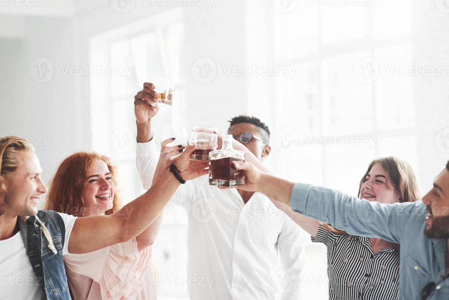 de hele dag feest. teamgenoten die whisky drinken en lachen vanwege een succesvolle deal foto