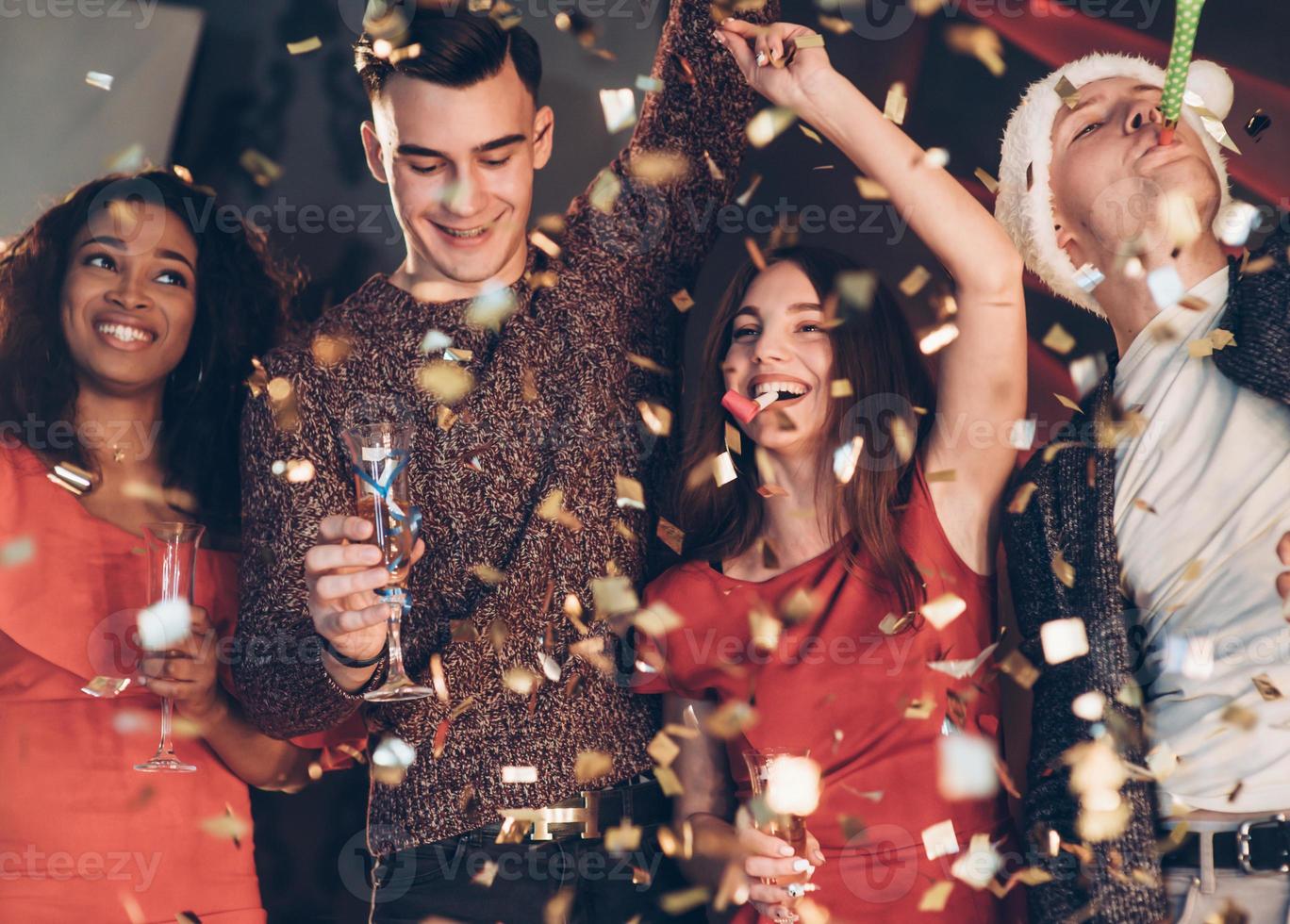 goed gezind. lucht in de confetti. vier goede vrienden in de goede kleren zijn op het feest van het nieuwe jaar foto