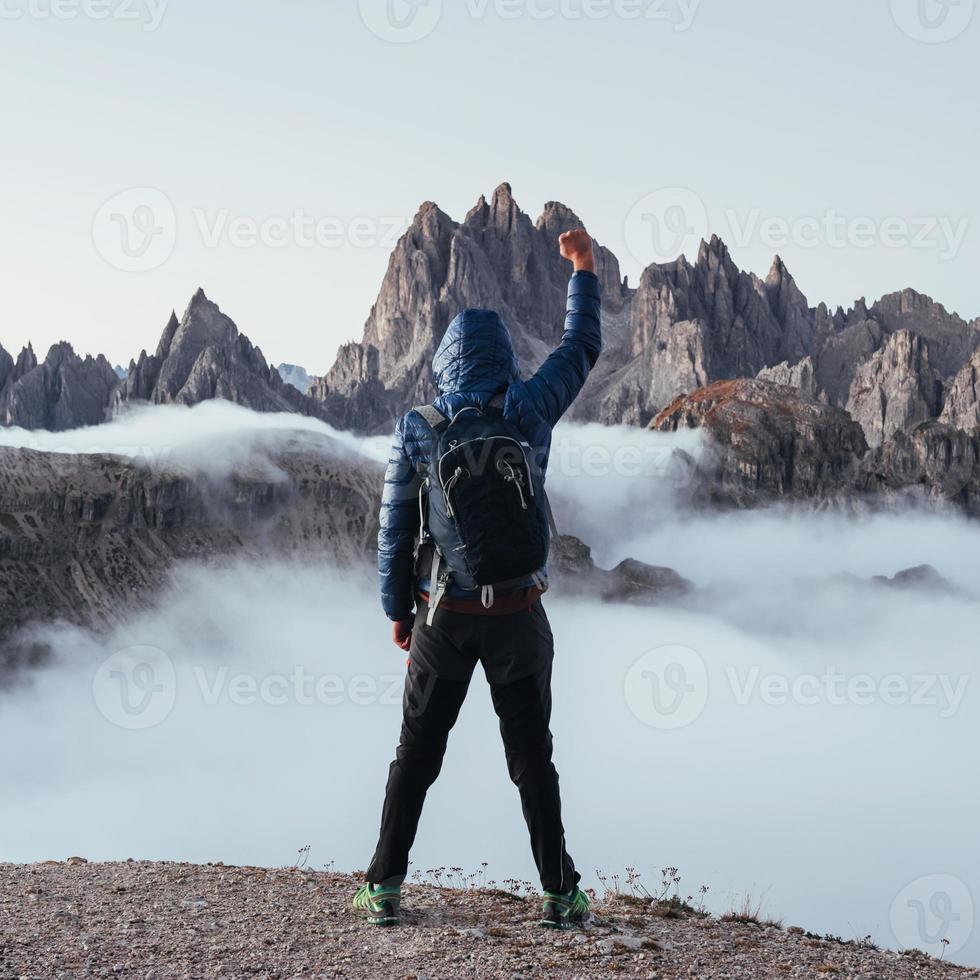 vuist opsteken. toeristische man stak zijn handen omhoog op de prachtige daglichtbergen vol mist foto