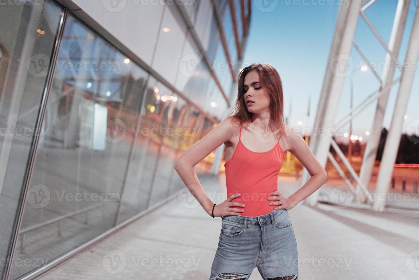 foto van een jong aantrekkelijk meisje dat op straat staat en haar handen om haar middel houdt