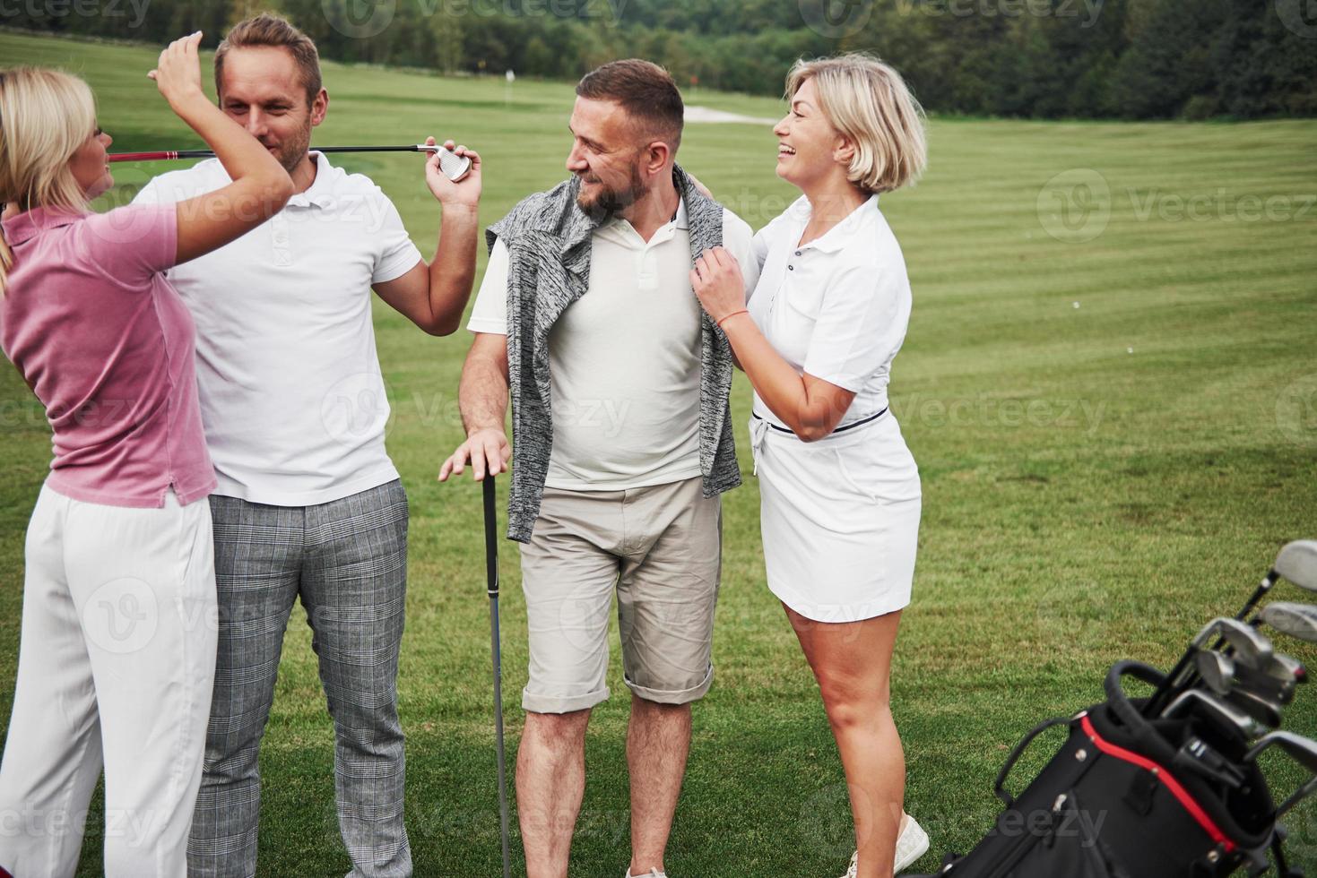 groep stijlvolle vrienden op de golfbaan leren een nieuw spel te spelen. het team gaat rusten na de wedstrijd foto