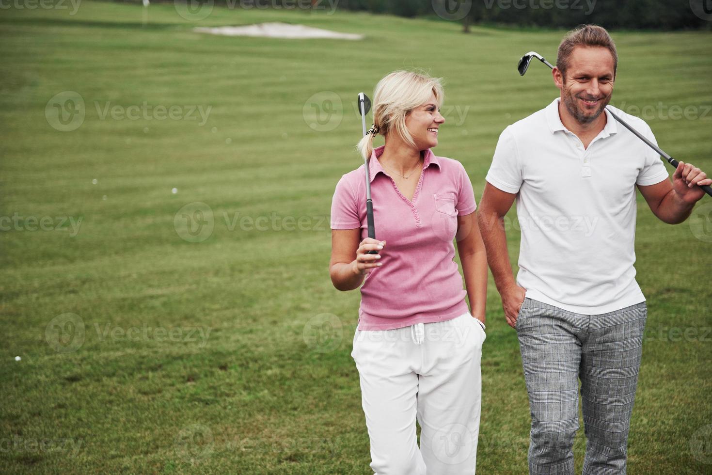 sportief paar dat golf speelt op een golfbaan, ze staan bij het volgende gat foto