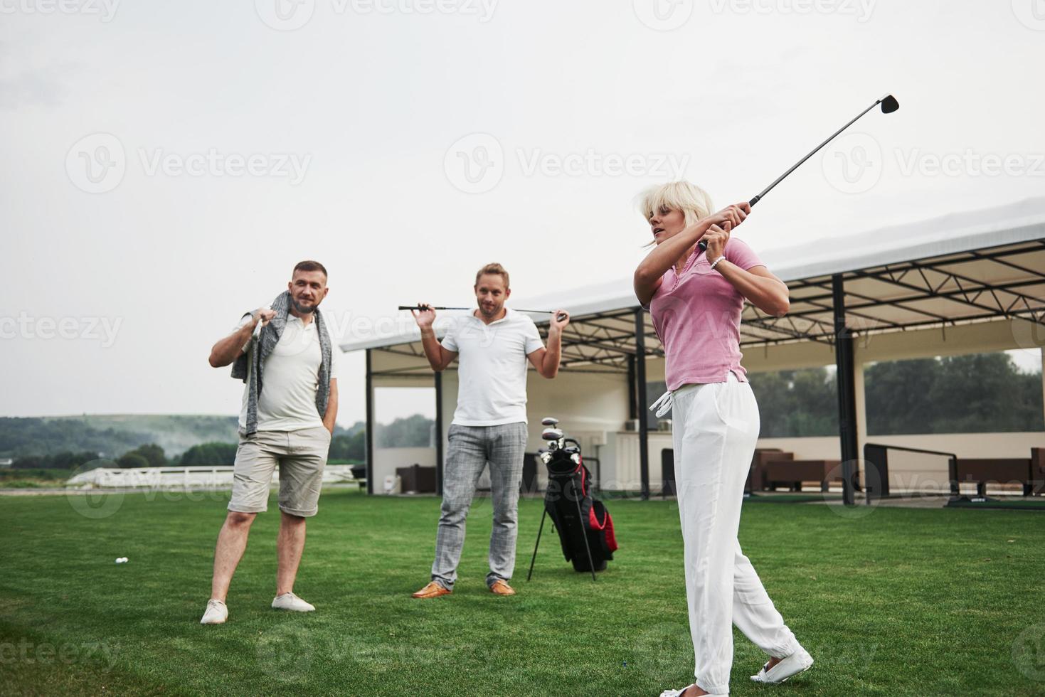 groep stijlvolle vrienden op de golfbaan leren een nieuw spel te spelen foto