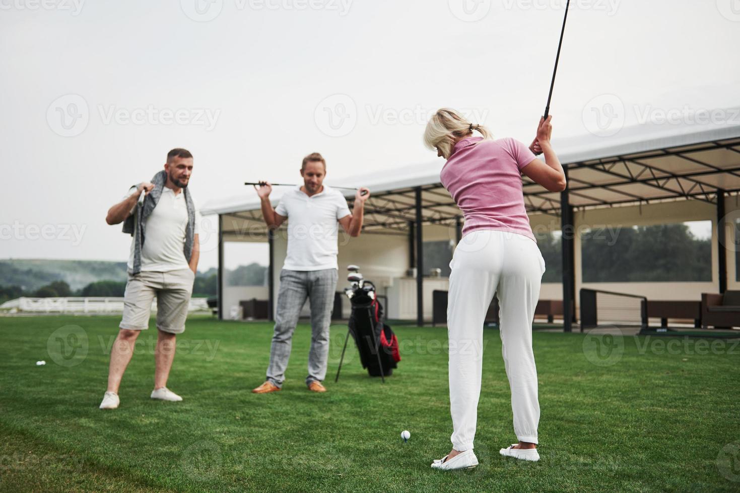 groep stijlvolle vrienden op de golfbaan leren een nieuw spel te spelen foto