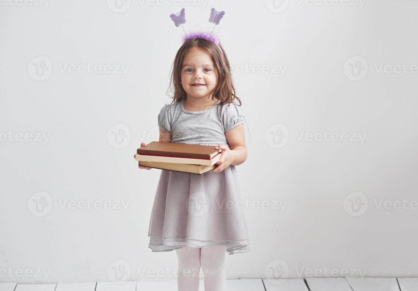 een klein meisje met wat schoolboeken in de kamer met een witte achtergrond foto