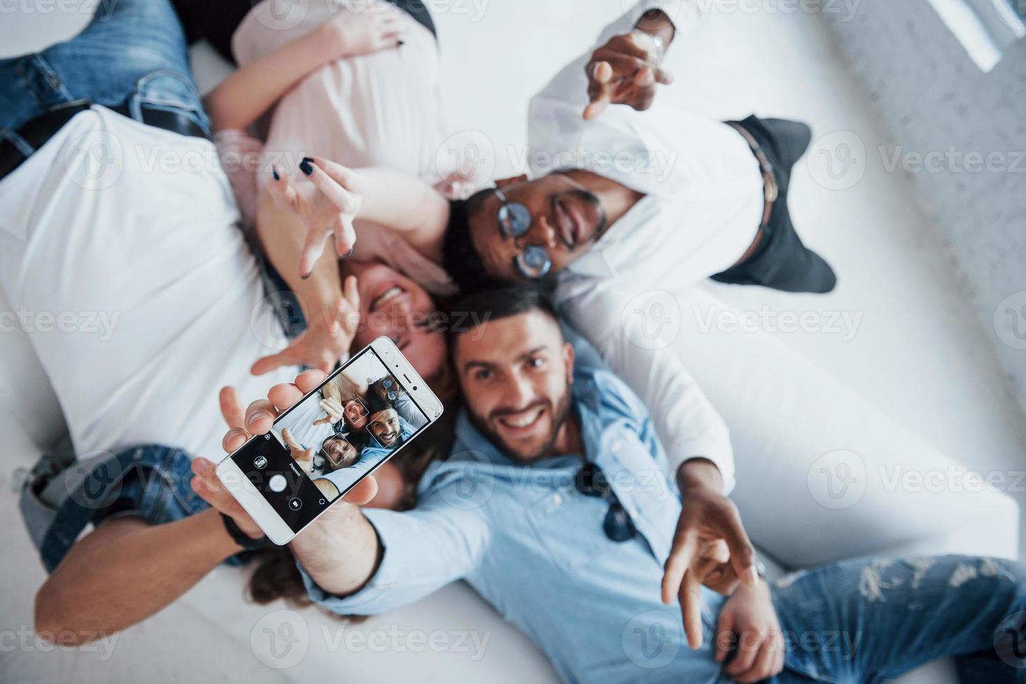 de armen optillen. jonge mensen die gaan liggen en een selfie maken met focus op de telefoon foto