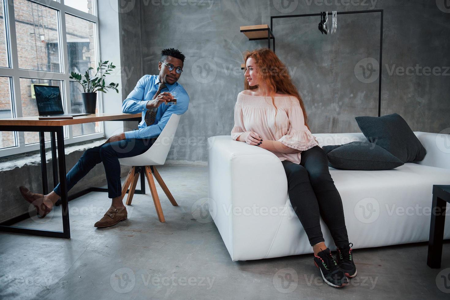 internationale collega's op kantoor hebben een pauze. de jongen biedt een meisje te drinken aan foto