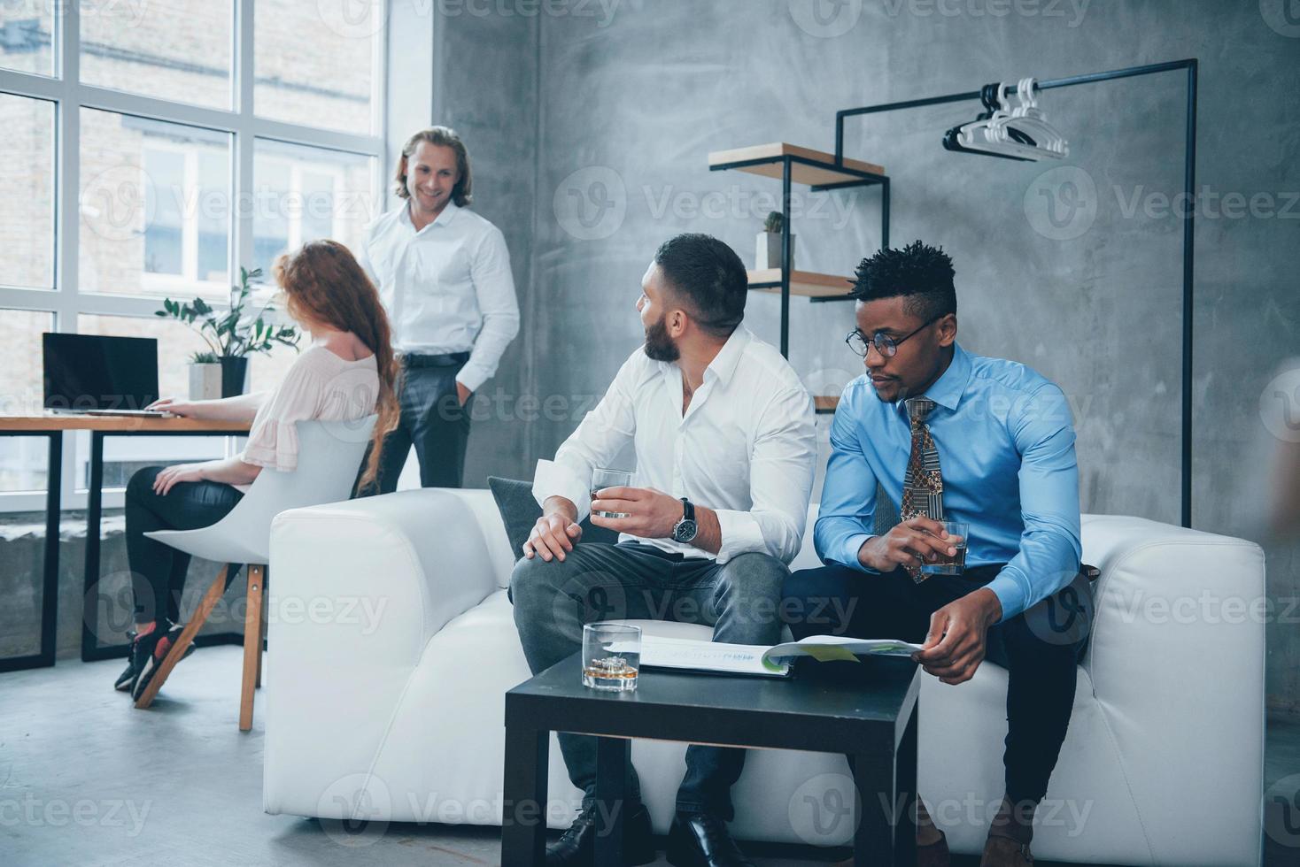 vriendelijke samenwerking. groep multiraciale kantoormedewerkers in formele kleding praten over taken en plannen foto