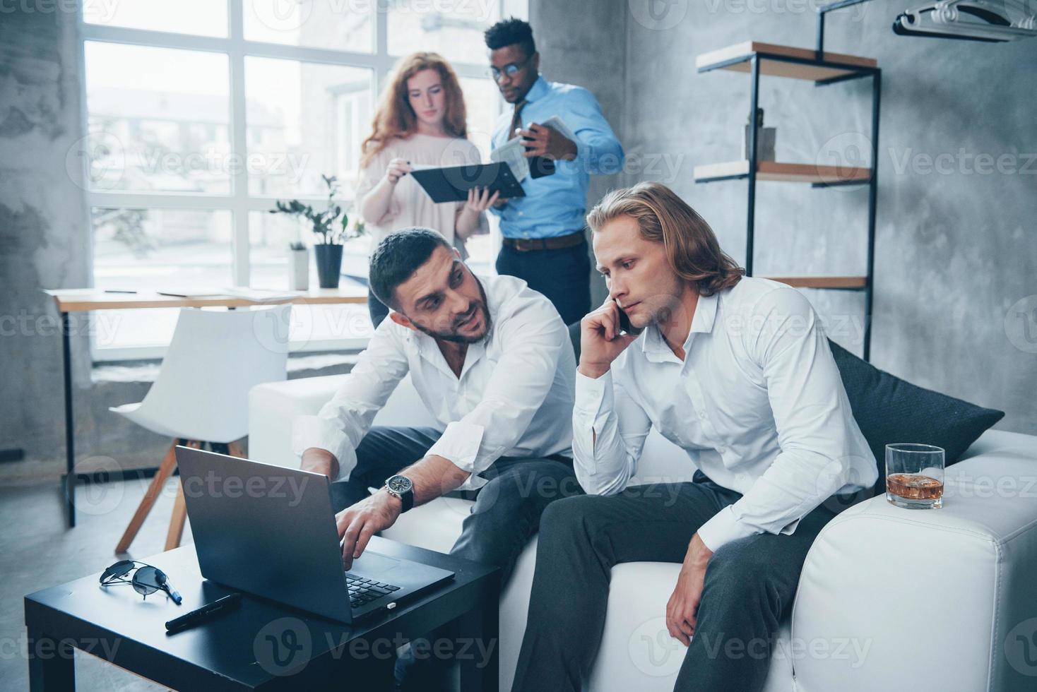 deadline komt eraan. groep multiraciale kantoormedewerkers in formele kleding praten over taken en plannen foto