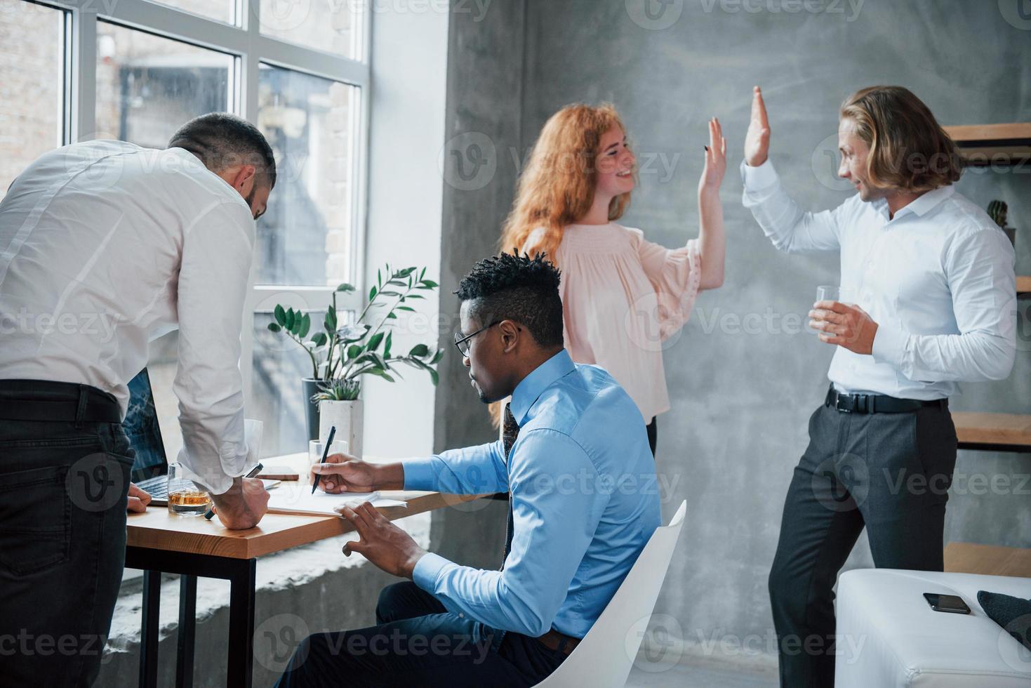 hoge vijf op de achtergrond. kantoorpersoneel vol met werk en het schrijven van routinerapporten foto