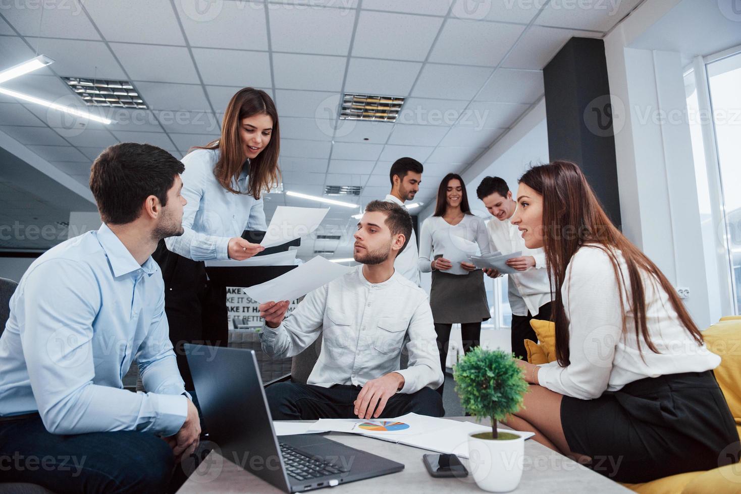 werk maar leuke sfeer. groep jonge freelancers op kantoor praten en glimlachen foto