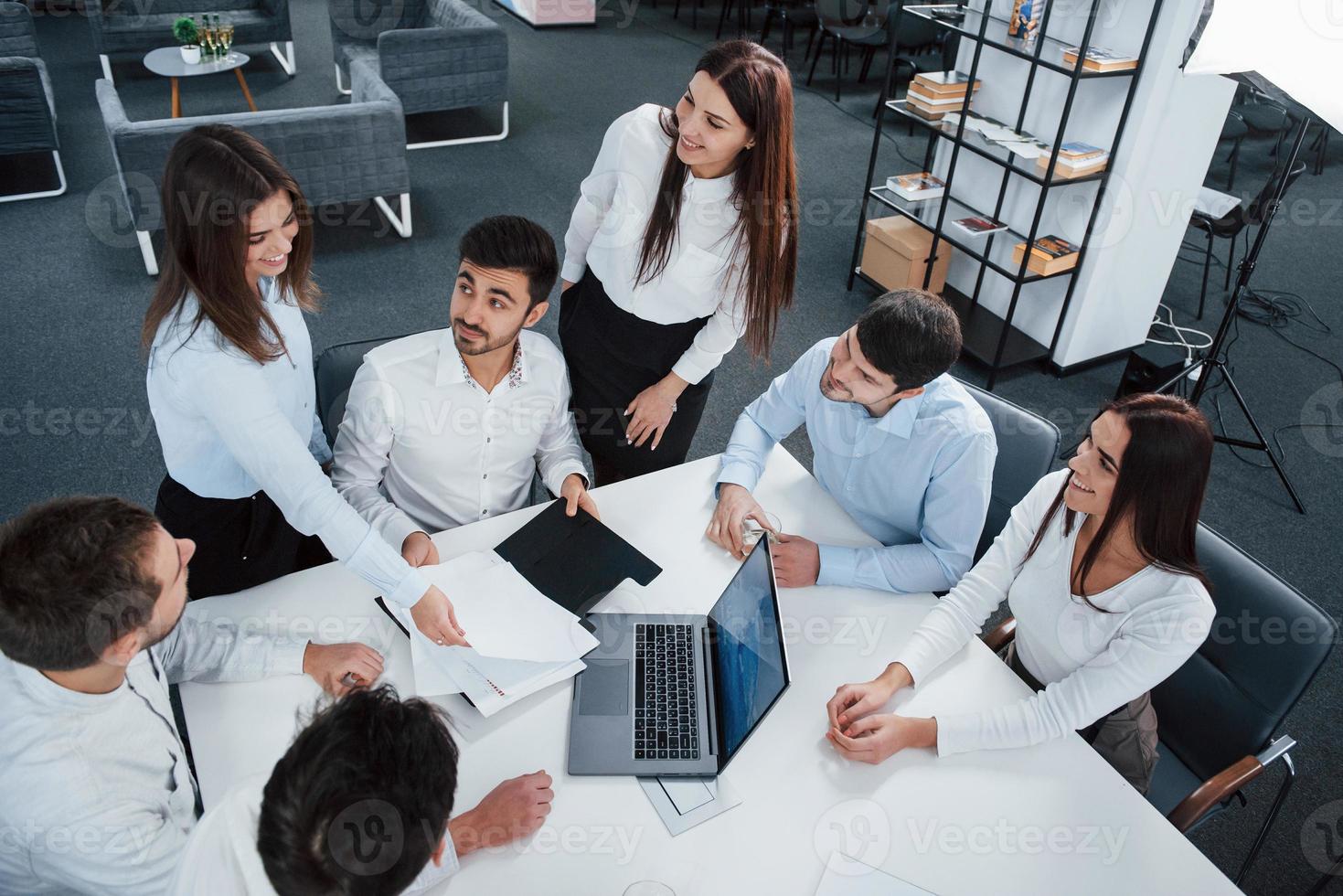 oogcontact noodzakelijk. bovenaanzicht van kantoormedewerkers in klassieke kleding die bij de tafel zitten met laptop en documenten foto