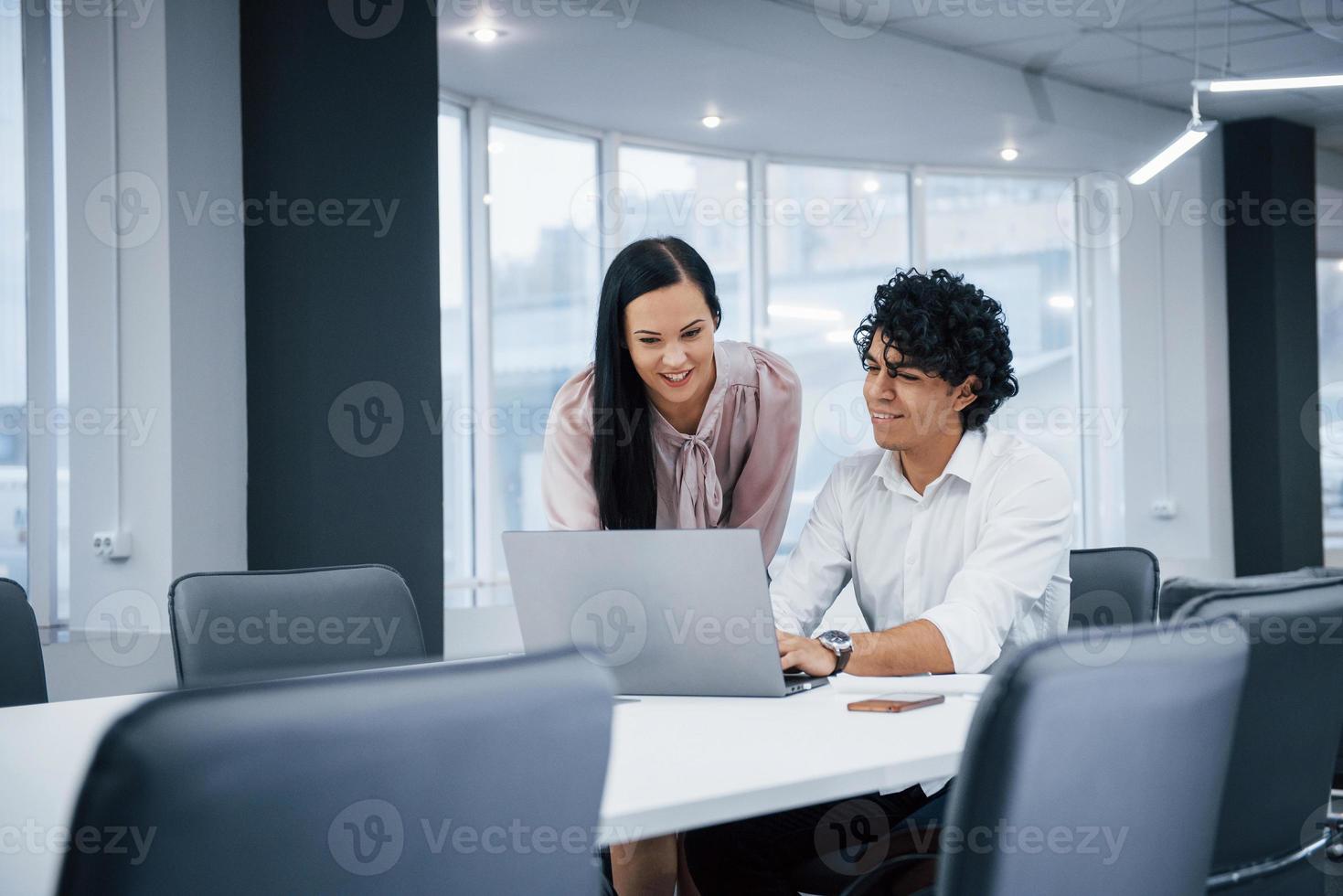 samen kijken naar de computer. vrolijke collega's in een modern kantoor die glimlachen als ze hun werk doen met een laptop foto